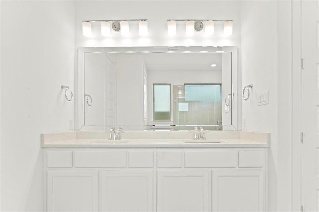 Dual vanity with white cabinetry, light-colored countertop, and two sets of chrome fixtures