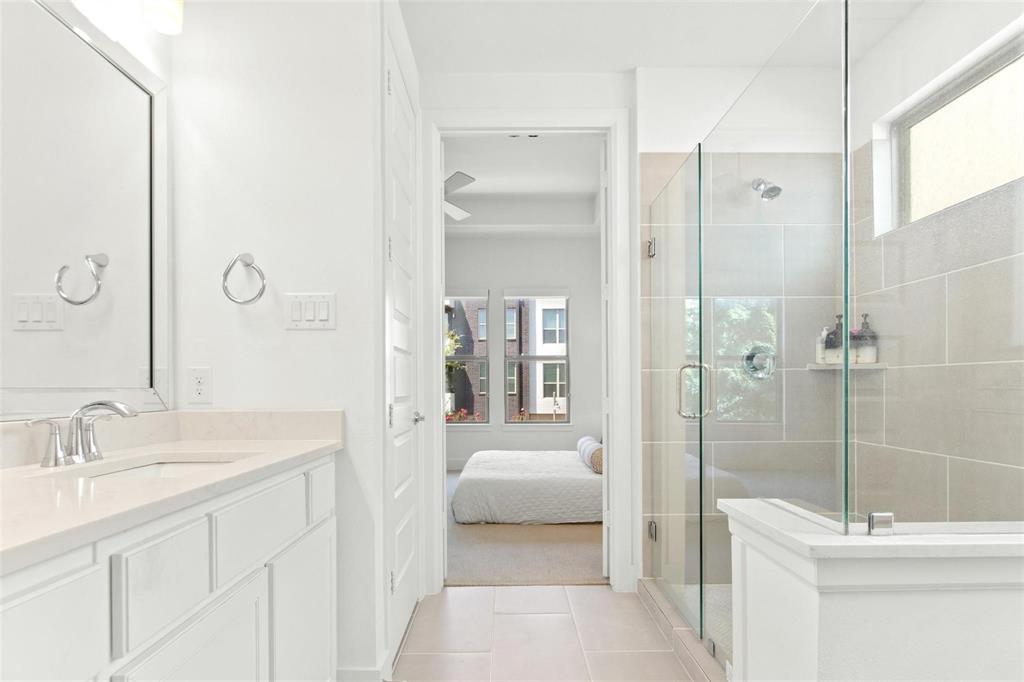 Bathroom featuring a glass-enclosed shower with large format tile surround, a built-in shower niche, and a fixed showerhead