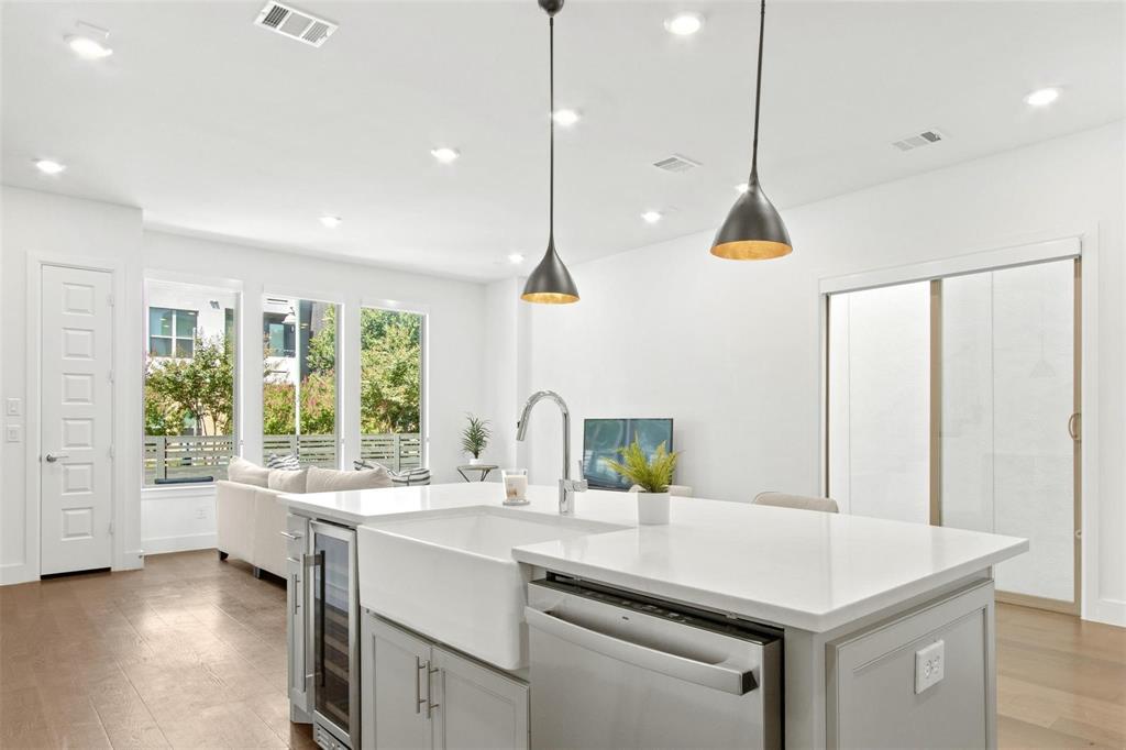 Kitchen island with a white farmhouse sink, stainless steel dishwasher, and built-in beverage cooler