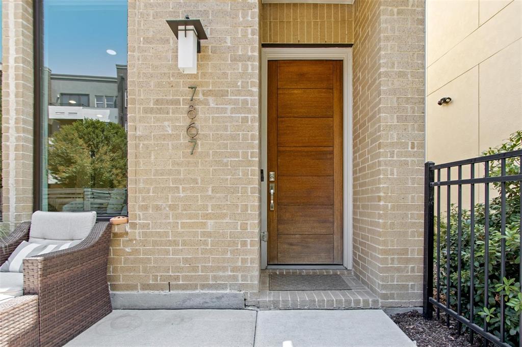 Contemporary wood-finish entry door with horizontal paneling, complemented by a modern exterior sconce