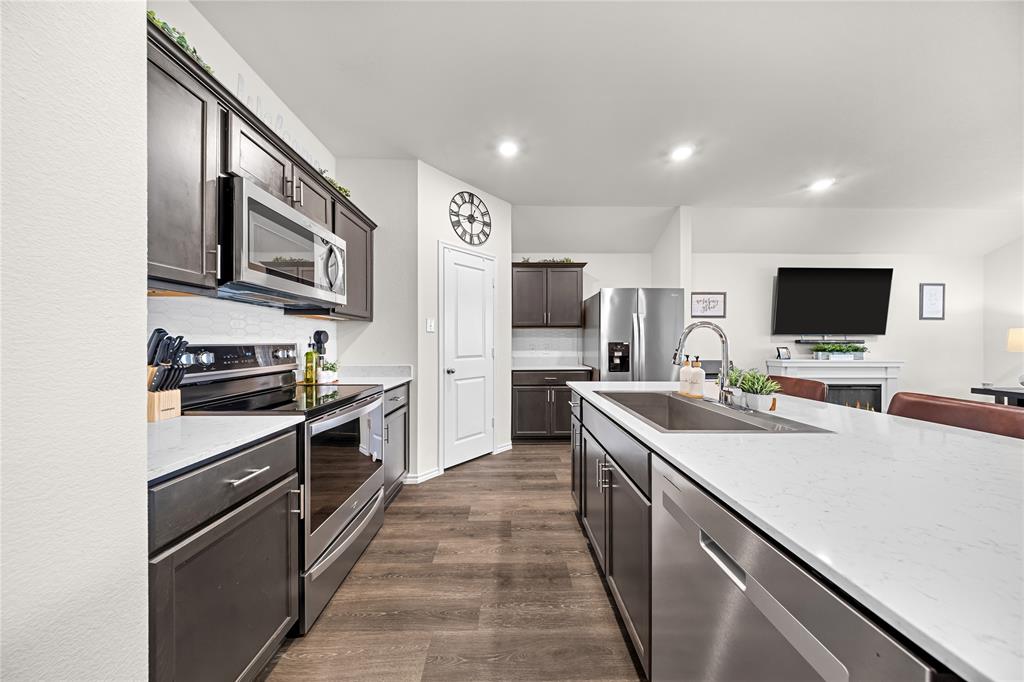 Chef's kitchen featuring stainless steel appliances, including dual wall ovens and a built-in microwave, paired with sleek black cabinetry and white quartz countertops