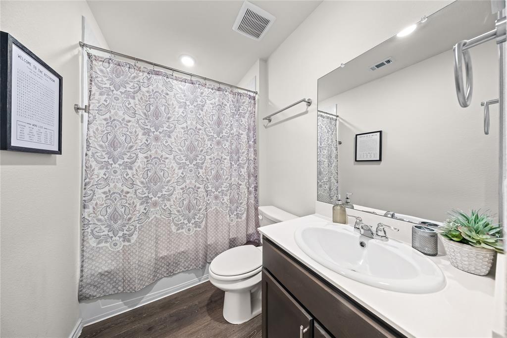 Bathroom featuring a dark wood-finish vanity, white countertop, oval undermount sink, and a framed mirror