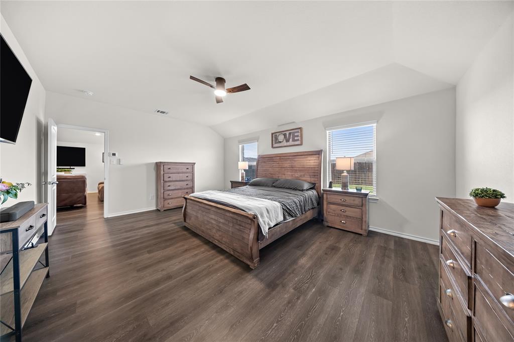 Spacious bedroom featuring dark wood-finish flooring, vaulted ceilings, and light-toned walls