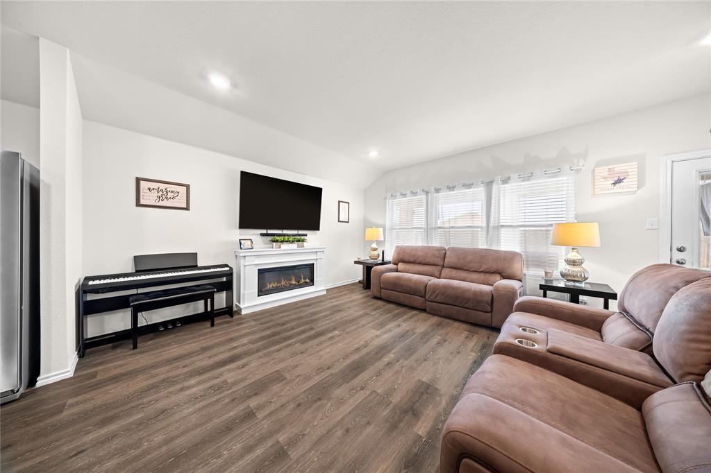 Spacious interior featuring wood-finish flooring, a contemporary fireplace with a white mantel, and multiple windows providing natural light