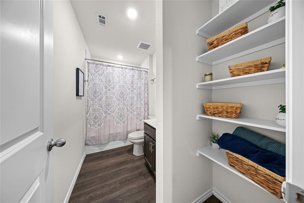Full bathroom featuring wood-finish flooring, a white toilet, and a dark wood-finish vanity with a white countertop