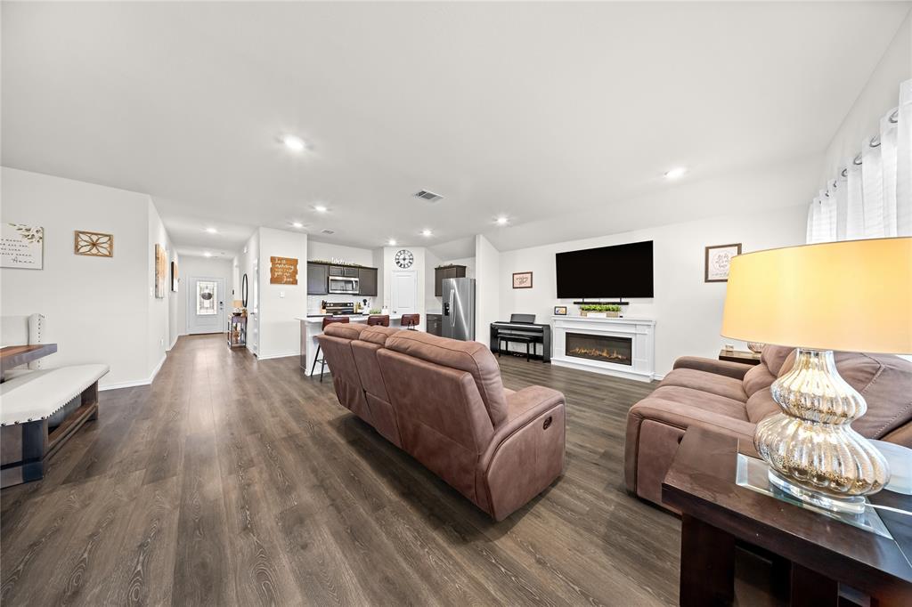 Open-concept living area featuring wood-finish flooring, recessed lighting, and a modern electric fireplace with a white mantel