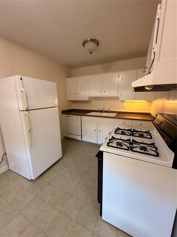 Kitchen featuring white cabinetry, a gas range, a double-basin sink, and vinyl tile flooring
