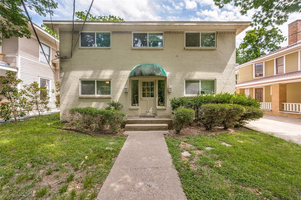 Charming two-story home featuring a cream brick exterior with a curved turquoise awning over the front entrance