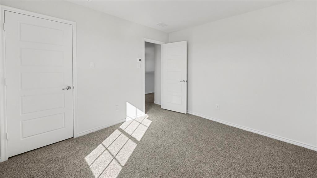 Carpeted room with a five-panel interior door and a second open doorway revealing an interior space