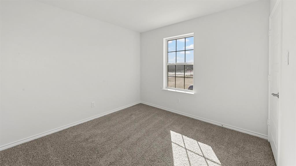 Carpeted room with a multi-pane window and a white door featuring a chrome handle