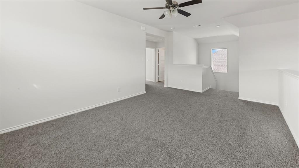 Spacious interior featuring neutral wall finishes, gray carpeting throughout, and a ceiling fan