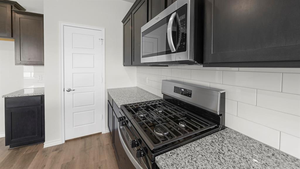 Modern kitchen featuring stainless steel gas cooktop with multiple burners, integrated microwave above the range, and granite-style countertops Modern kitchen featuring stainless steel gas cooktop with multiple burners, integrated microwave above the range, and granite-style countertops