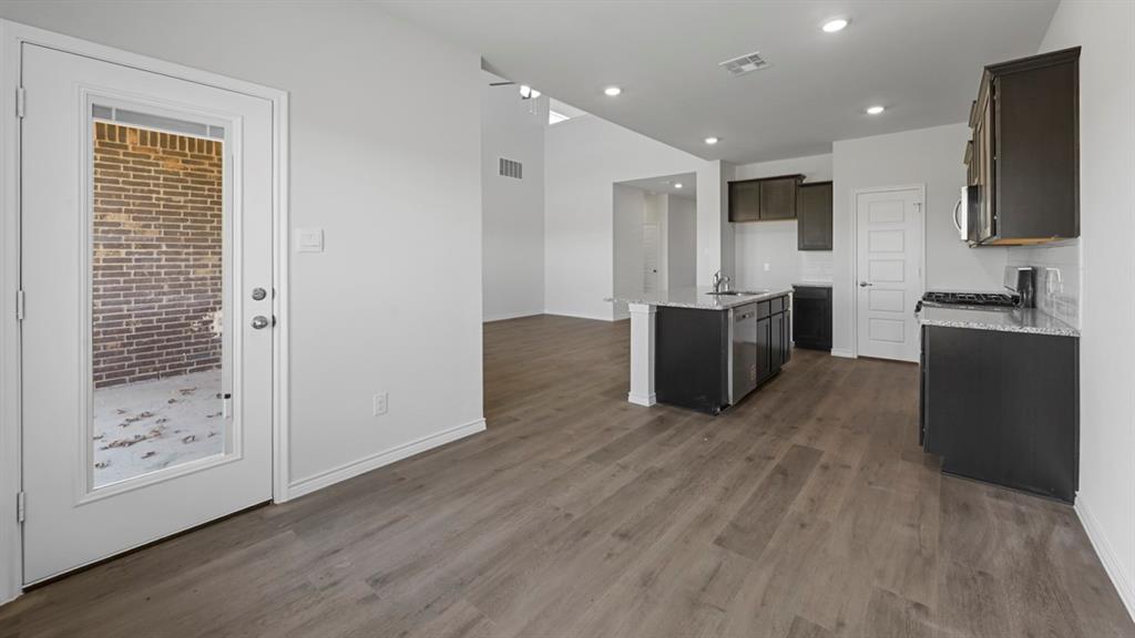 Open-concept kitchen with dark cabinetry, granite-style countertops, and a subway tile backsplash Open-concept kitchen with dark cabinetry, granite-style countertops, and a subway tile backsplash