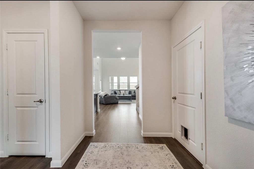 Elegant foyer featuring clean-lined white panel doors, warm neutral walls, and dark wood-finish flooring