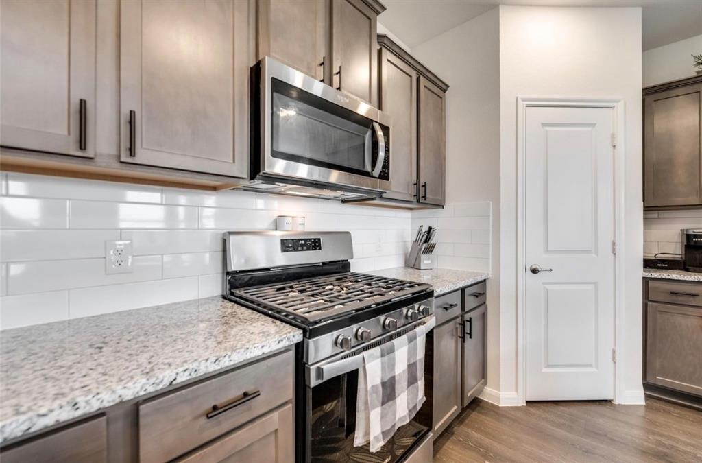 Kitchen featuring stainless steel appliances, light wood-finish cabinetry, granite-style countertops, and a white subway tile backsplash