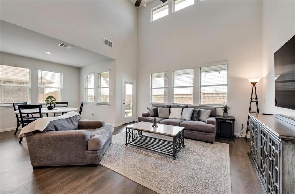 Two-story living area with high ceilings, upper transom windows, and wood-finish flooring
