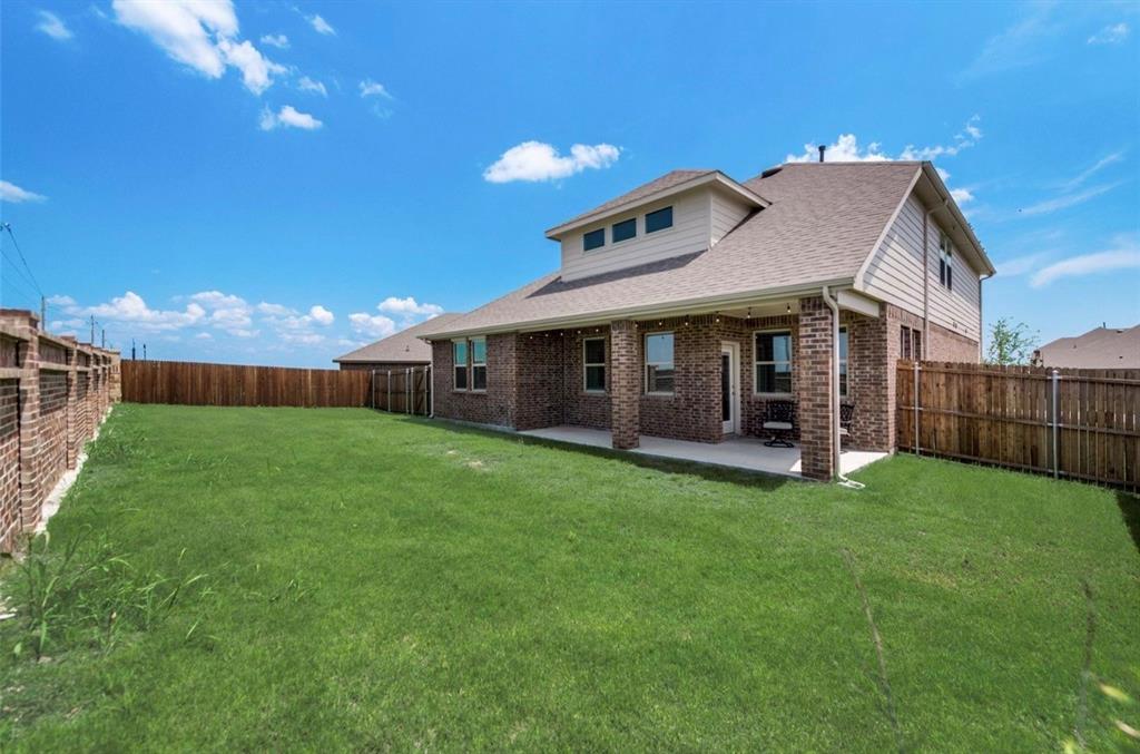 Expansive green lawn with a covered patio, brick columns, and a full privacy fence