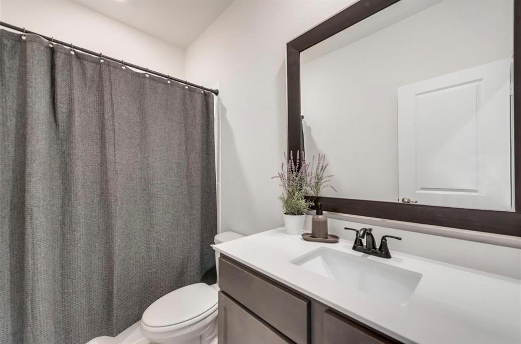 Modern bathroom featuring a white quartz countertop with an undermount sink, matte black faucet and hardware, and ample mirror with dark frame detailing