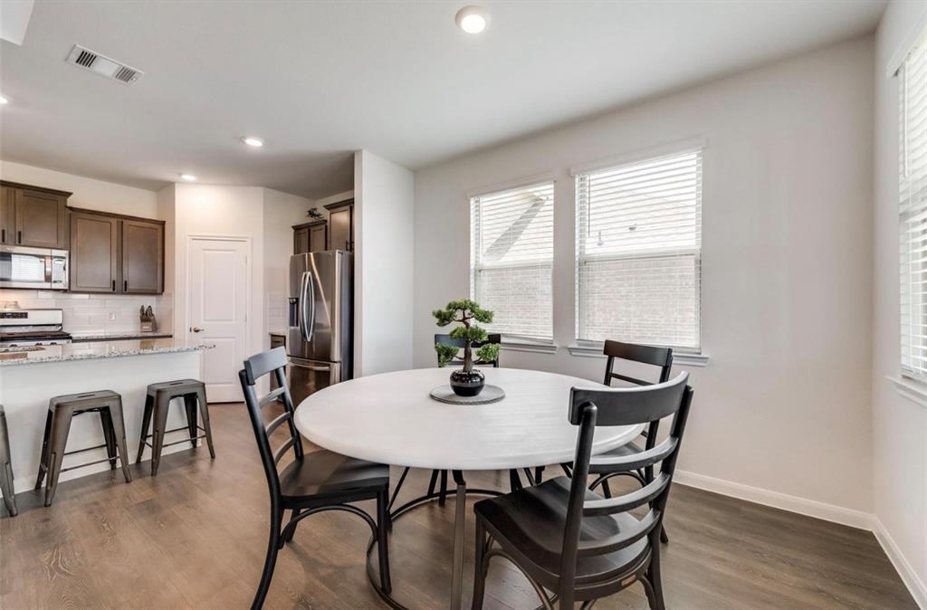 Kitchen and dining area featuring wood-finish flooring, recessed lighting, and multiple windows with blinds