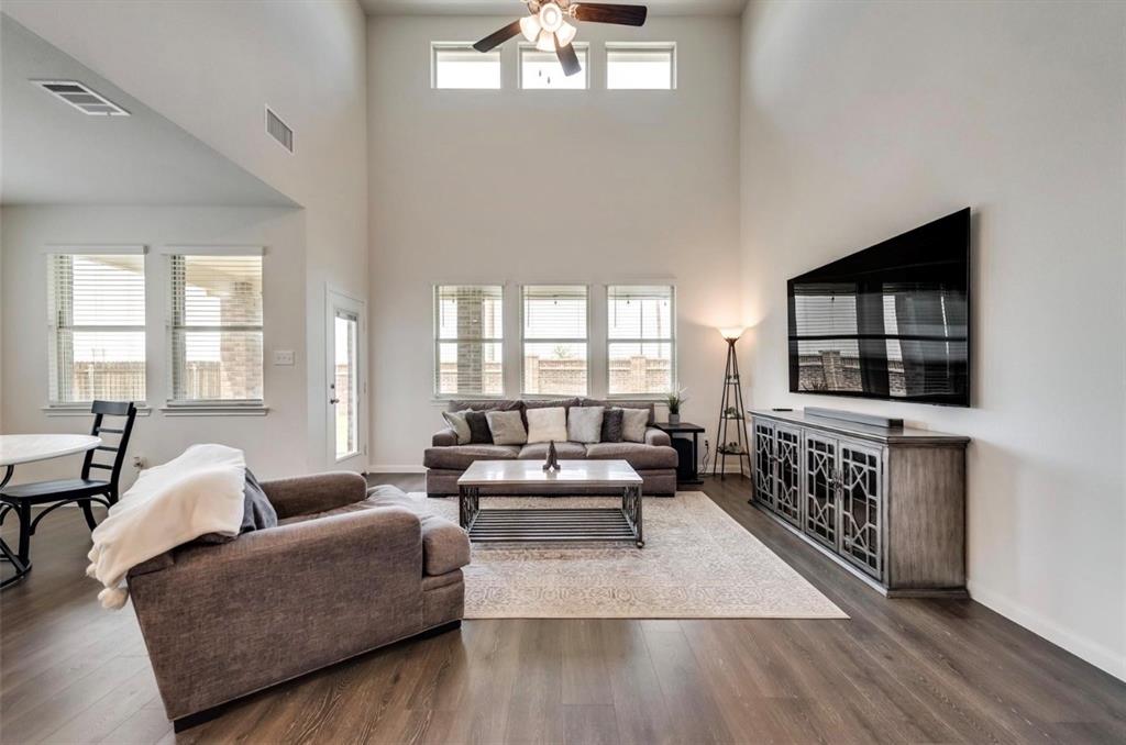 Living area with vaulted ceilings, wood-finish flooring, and multiple windows