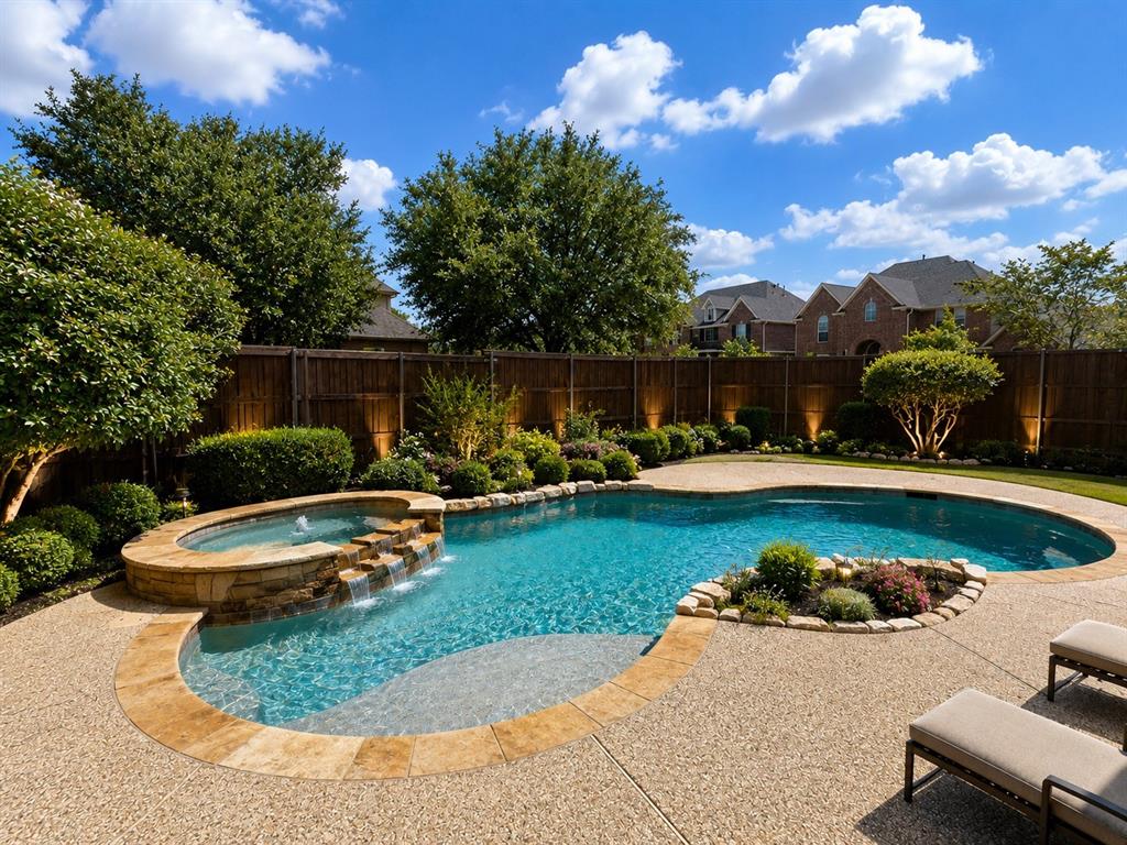 Resort-style backyard featuring a freeform pool, integrated spa with stone waterfall, and expansive aggregate patio Resort-style backyard featuring a freeform pool, integrated spa with stone waterfall, and expansive aggregate patio