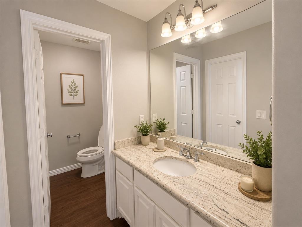 Bathroom featuring a single vanity with an integrated sink, polished chrome faucet, and a stone countertop