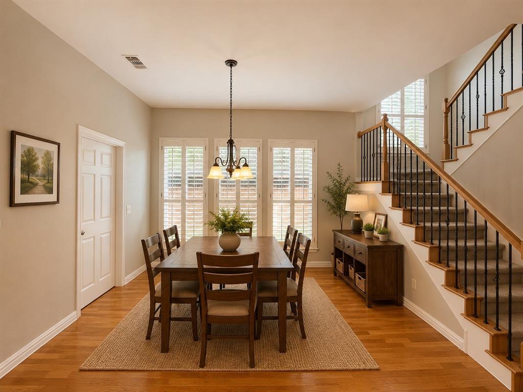 Dining space with wood-finish flooring, plantation shutters, and a chandelier