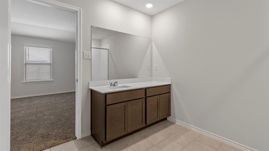 Bathroom vanity featuring a single sink, light-colored countertop, and dark wood-finish cabinetry