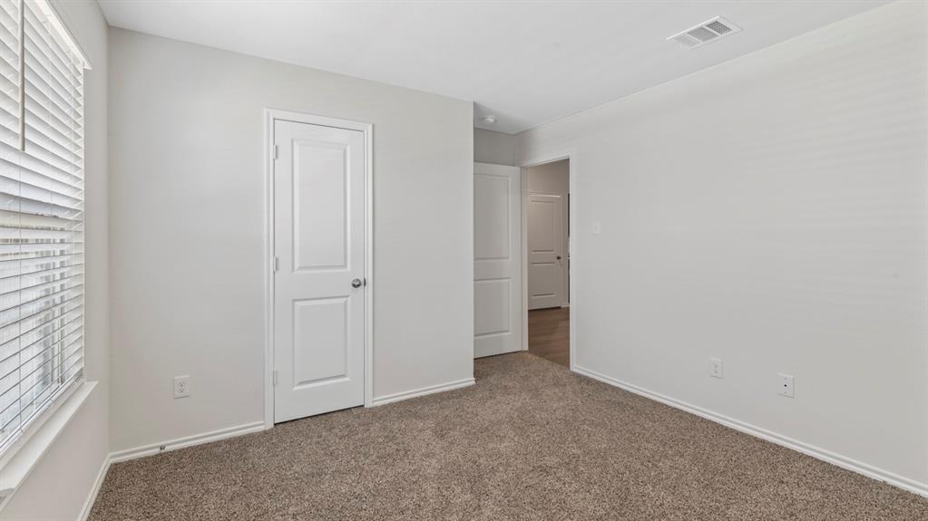 Carpeted room featuring a window with horizontal blinds, white baseboards, and two paneled interior doors