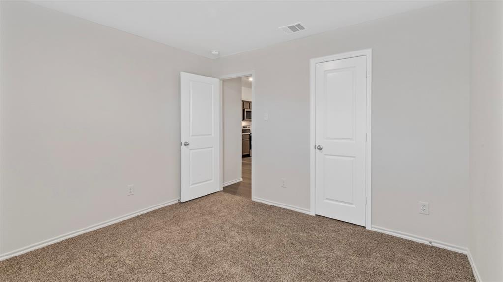 Carpeted room featuring light gray walls, white baseboards, and two white paneled doors