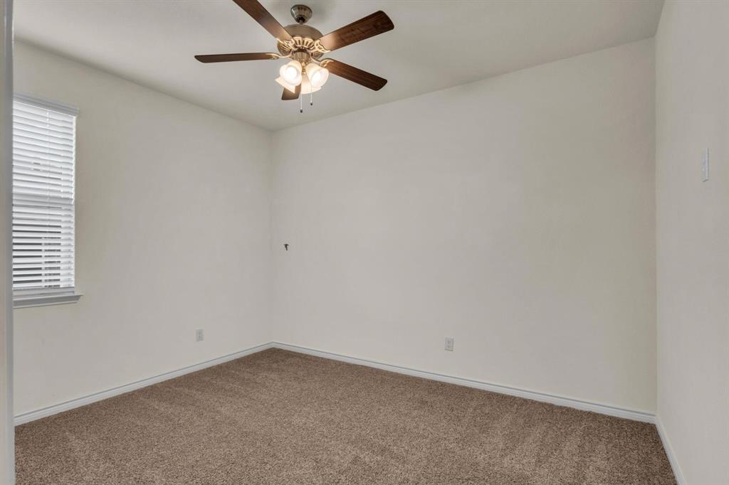 Neutral tone wall paint, textured carpet flooring, window with horizontal blinds, and a ceiling fan with integrated lighting