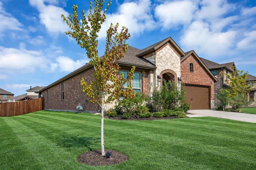 Stone and brick facade featuring an arched entryway, attached two-car garage, concrete driveway, and manicured front lawn Stone and brick facade featuring an arched entryway, attached two-car garage, concrete driveway, and manicured front lawn