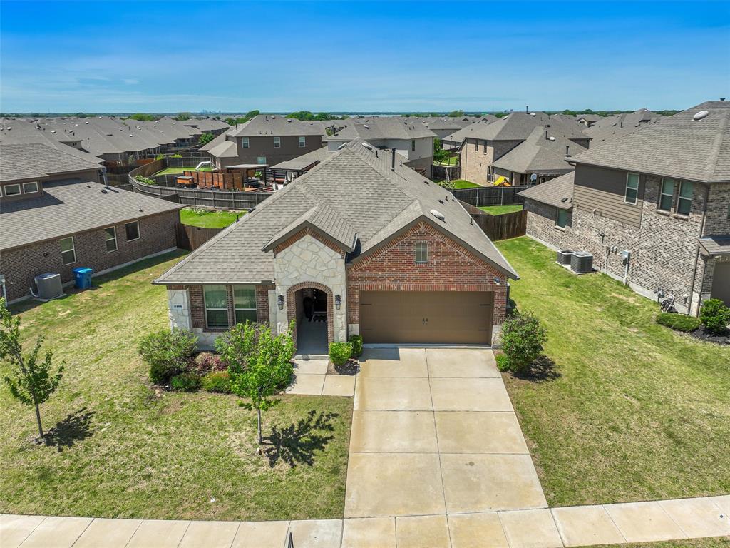Charming brick-front home featuring a two-car garage, manicured front lawn with established landscaping, concrete driveway, and arched entryway