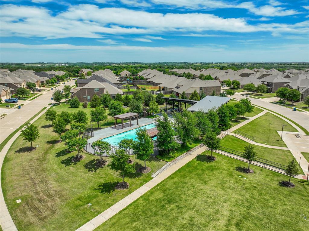 Community pool and recreation area featuring a covered patio, paved walkways, and extensive green spaces