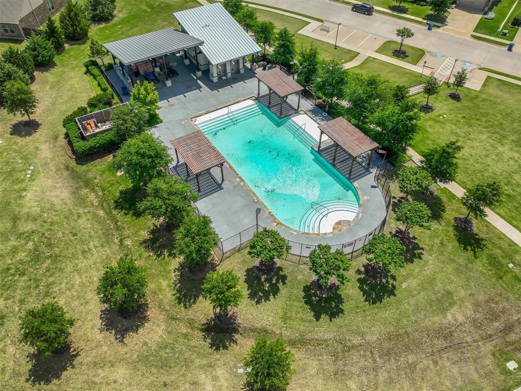 Charming brick-front home featuring a two-car garage, manicured front lawn with established landscaping, concrete driveway, and arched entryway
