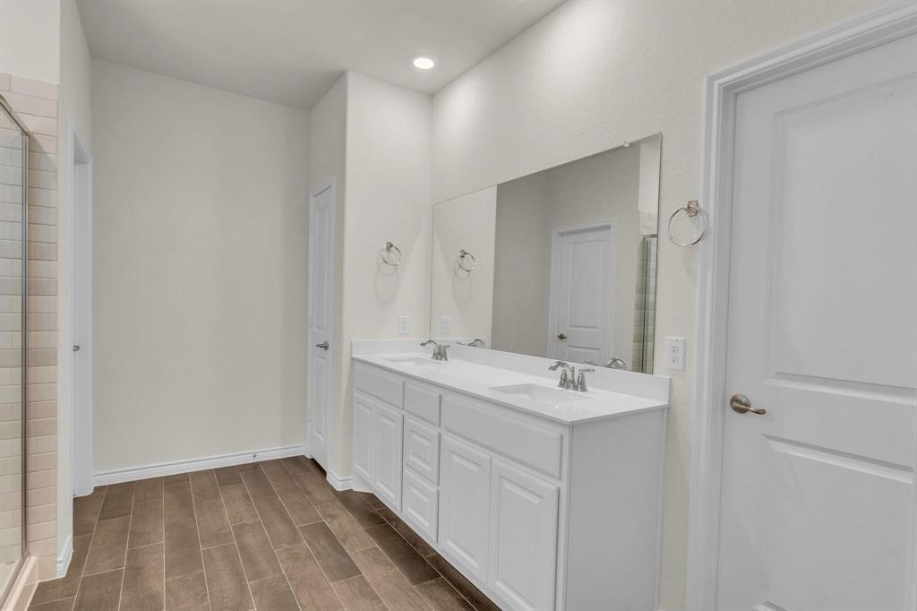 Bathroom featuring a dual vanity with white cabinetry, integrated sinks, and a large wall-mounted mirror
