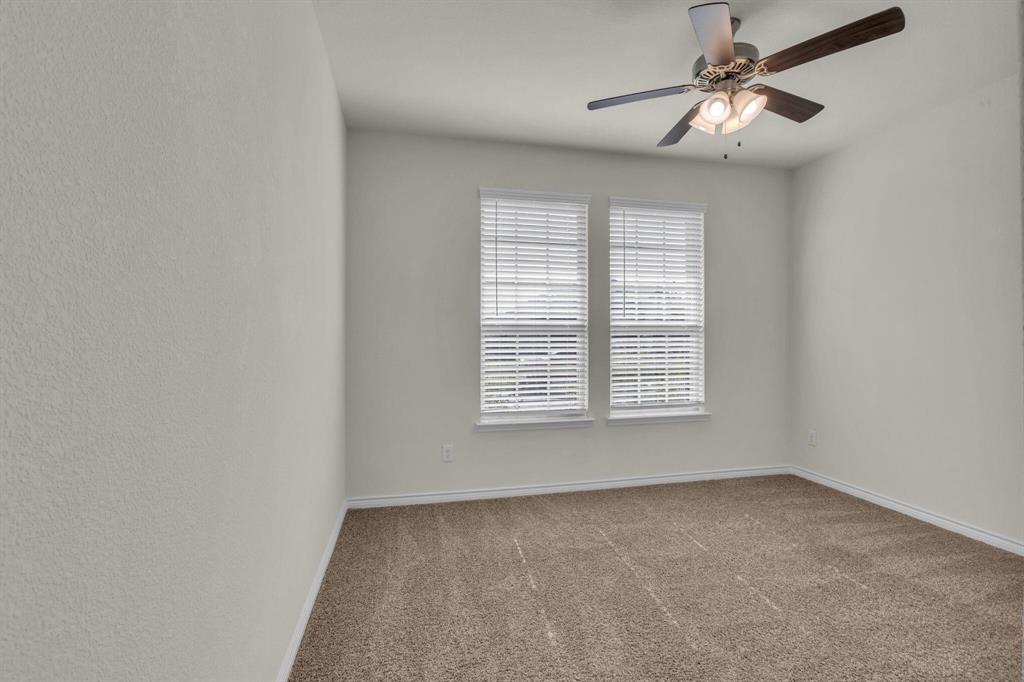 Bedroom featuring two windows with white blinds, neutral carpeting, light-toned walls, and a ceiling fan with integrated lighting