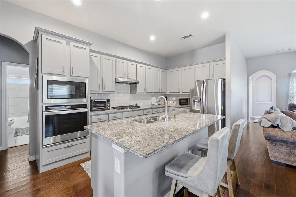 Kitchen featuring light gray cabinetry, stainless steel appliances, and large island Kitchen featuring light gray cabinetry, stainless steel appliances, and large island