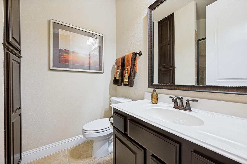 This guest suite bathroom features a walk-in shower, ample storage cabinetry, bronze-finish fixtures, a framed mirror, and tile flooring.