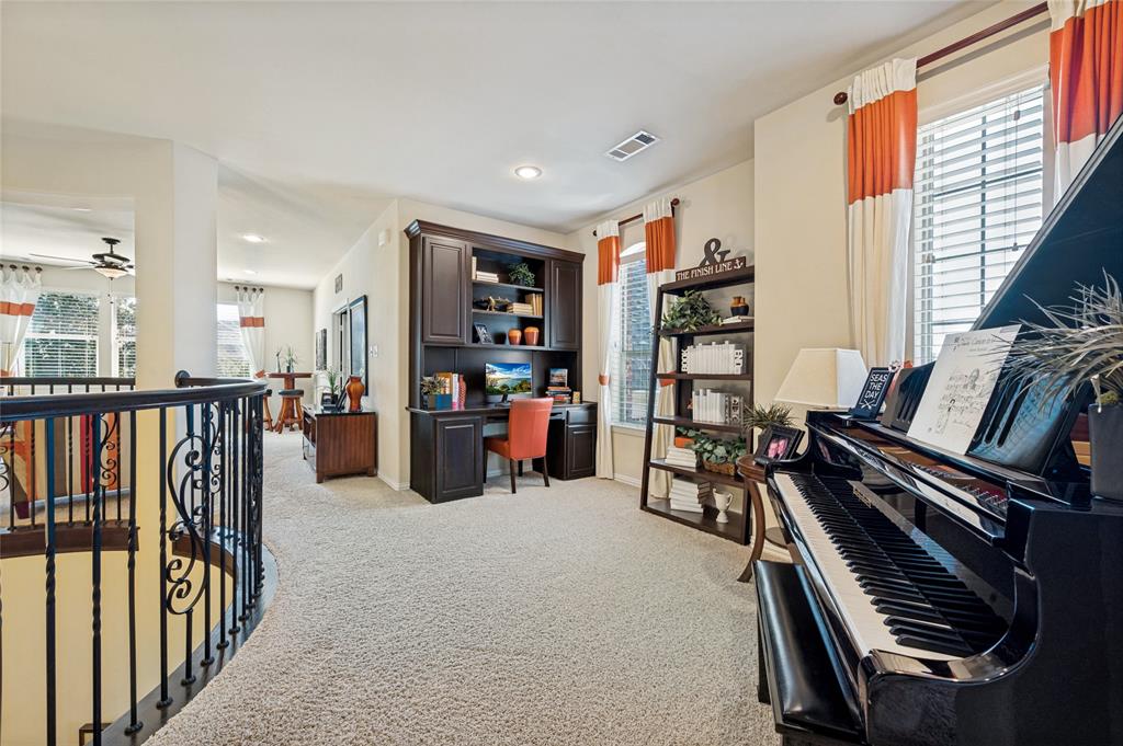 The upstairs area features a spacious built-in desk complemented by custom cabinetry, integrated shelving, and elegant recessed lighting.