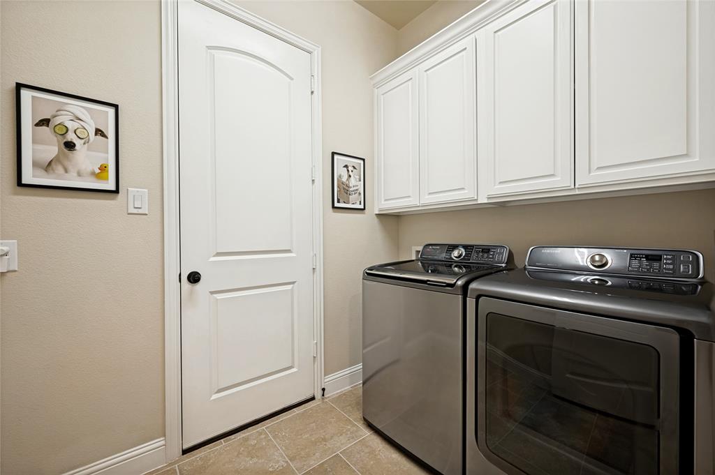 The utility room features custom white paneled cabinetry providing ample storage, with designated space for a full-sized washer and dryer.