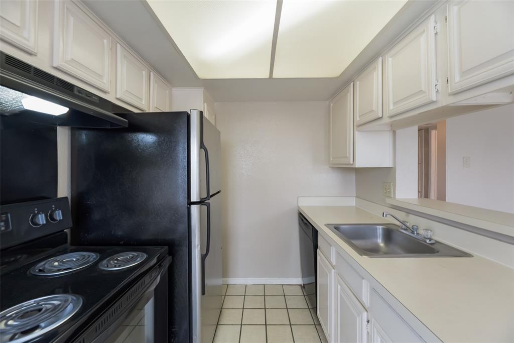 Kitchen with sink, black appliances, white cabinetry, and light tile floors