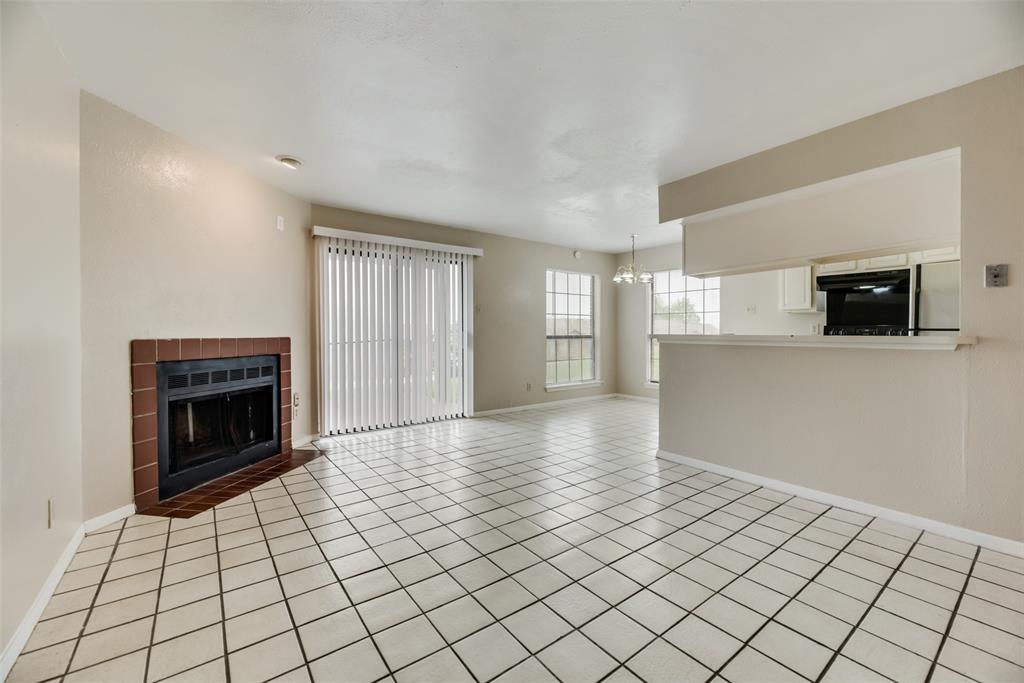 Unfurnished living room featuring an inviting chandelier, light tile floors, and a fireplace