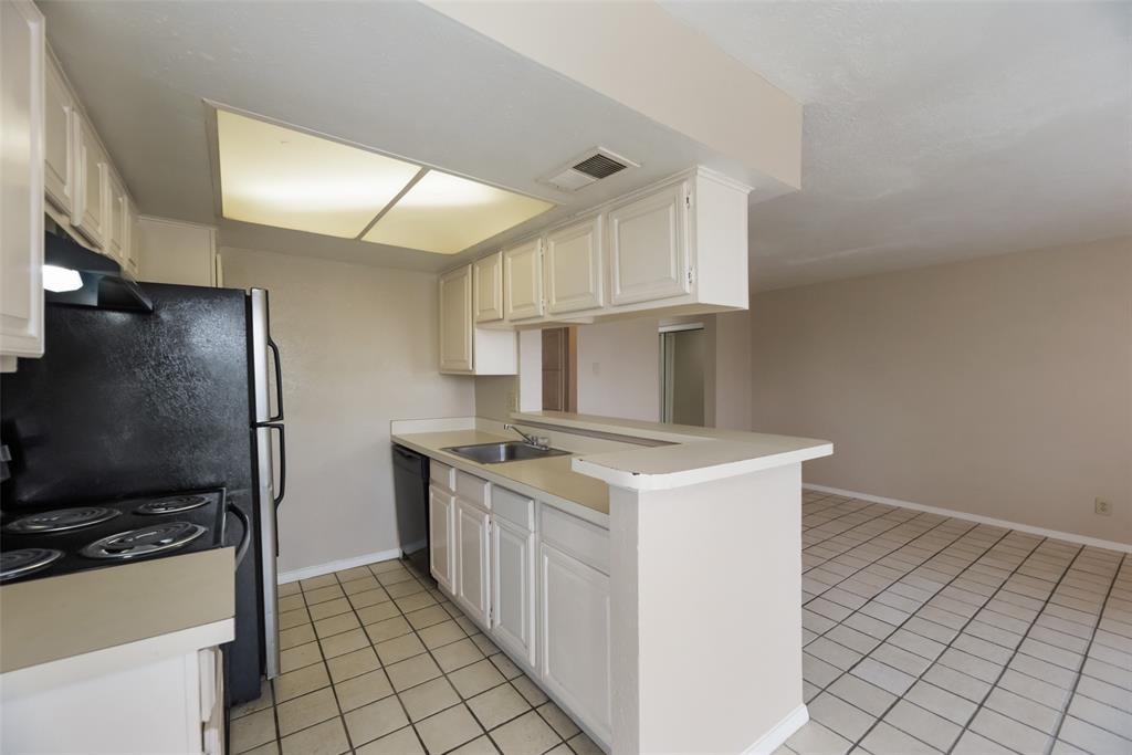 Kitchen with light tile flooring, white cabinetry, kitchen peninsula, sink, and dishwasher