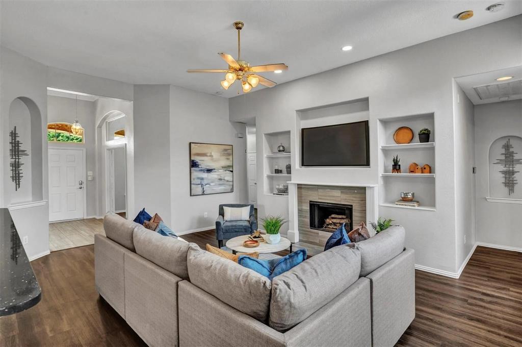 Open-concept living room anchored by a linear fireplace with built-in shelving and a mounted television