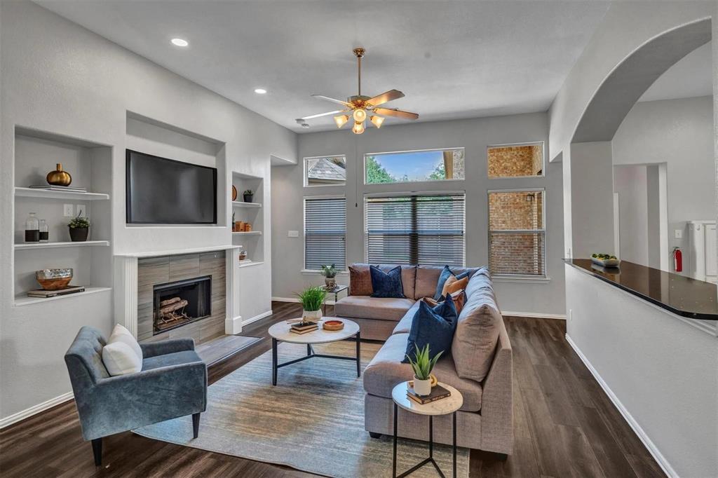 Sophisticated living room showcasing hardwood flooring, a linear gas fireplace with built-in cabinetry, and recessed ceiling lighting
