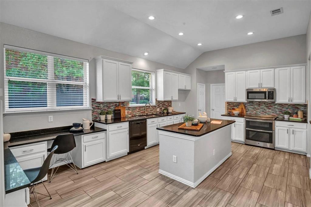 Kitchen featuring a central island, recessed lighting, wood-finish flooring, white cabinetry, and stainless steel appliances