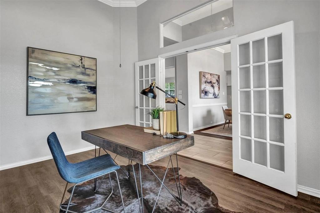 Wood-finish flooring with crisp white baseboards, vaulted ceilings, and double French doors with transom window