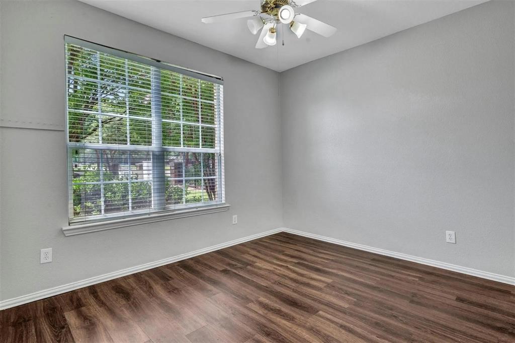 Wood-finish flooring, ceiling fan with integrated lighting, window with blinds, and light gray wall finish