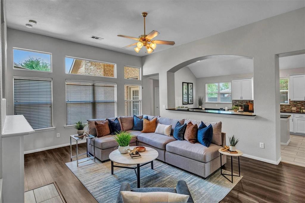 High ceilings, wood-finish flooring, built-in ceiling fan, arched doorway, and a kitchen pass-through with a breakfast bar